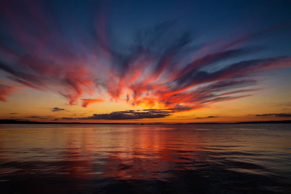 sunset over water. dark blue sky with orange, red and yellow sunset